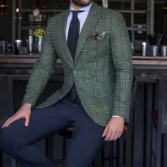 Elegancki mężczyzna w zielonej marynarce w kratę i granatowych spodniach. Idealne połączenie, jeśli zastanawiasz się, jakie spodnie do zielonej koszuli.