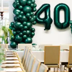 Uroczyste przyjęcie z okazji 40 urodzin w stylu lat 80. Zielone balony tworzą łuk z liczbą 40. Stoły nakryte do kolacji.