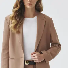 Elegancka brązowa marynarka w połączeniu z białą koszulką i czarnym paskiem tworzy stylową, minimalistyczną stylizację.