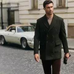 Elegancki mężczyzna w dwurzędowym płaszczu, pokazujący, jak nosić płaszcz męski. W tle klasyczny samochód.