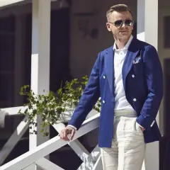 Elegancki mężczyzna w granatowej marynarce i beżowych spodniach, prezentujący styl ivy league.