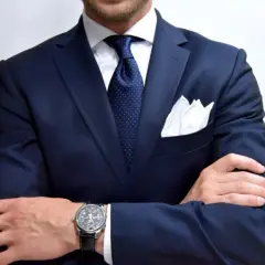 Elegancki mężczyzna w granatowej marynarce, białej koszuli i krawacie w kropki. Zastanawiasz się, jaki krawat do granatowej koszuli? Ten zestaw wygląda świetnie!