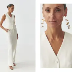 Elegancka stylizacja semi casual: biały garnitur z kamizelką i szerokimi spodniami, uzupełniony o długie, złote kolczyki.