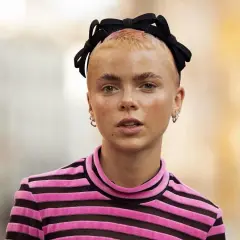Krótkie, blond włosy z różowymi końcówkami ozdobione czarną opaską z kokardą. Taka opaska na włosach to świetny sposób na podkreślenie stylizacji.