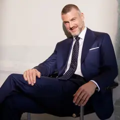 Elegancki mężczyzna w granatowym garniturze i wzorzystym krawacie. Idealny przykład, jak dobrać krawat do garnituru, by stworzyć spójną stylizację.
