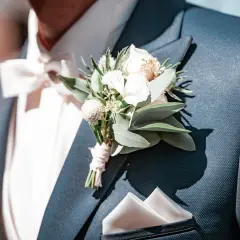 Elegancki, granatowy garnitur z białą poszetką i delikatnym kwiat w butonierce.