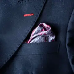 Elegancka poszetka w paisley do granatowego garnituru, z subtelnym czerwonym przeszyciem na klapie.
