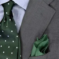 Elegancki zestaw: niebieska koszula, zielony krawat w kropki i szara marynarka. Idealna odpowiedź na pytanie: jaki krawat do niebieskiej koszuli.