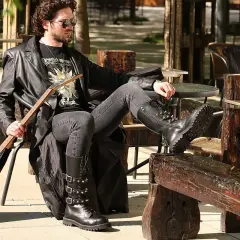 Mężczyzna w skórzanej kurtce i czarnych jeansach, idealnych jako spodnie do glanów, siedzi z gitarą.