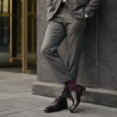 Elegancki mężczyzna w szarym garniturze i bordowych skarpetkach w kropki. Idealne połączenie, które odpowiada na pytanie: jakie skarpetki do garnituru?