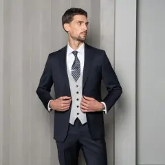 Elegancki mężczyzna w granatowym garniturze, jasnej kamizelce i wzorzystym krawacie. Idealna inspiracja, jaki krawat do czarnego garnituru wybrać.