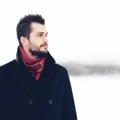 Mężczyzna w granatowym płaszczu i bordowym szaliku z wzorem. Idealny przykład, jaki szalik do granatowego płaszcza wybrać, by wyglądać stylowo.