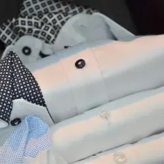 Stos eleganckich, białych koszul z mankietami i kołnierzykami w granatowe wzory. Czy to fular, co to za dodatek?