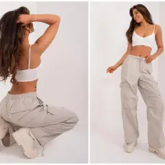 Luźne spodnie cargo w beżowym kolorze, idealne dla każdej sylwetki. Modelka prezentuje je w dwóch pozach, podkreślając ich wygodę i styl.
