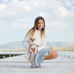 Dziewczyna w swetrze i kwiecistej sukience, z chihuahuą na rękach, prezentuje swój letni styl ubierania na tle jeziora.