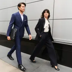 Para idąca w stylu business formal. Mężczyzna w granatowym garniturze, kobieta w ciemnym.