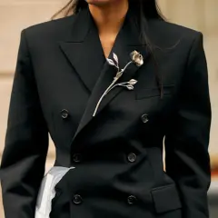 Elegancka broszka w kształcie róży na klapie czarnej marynarki. Inspiracja, jak nosić broszkę, by podkreślić styl.