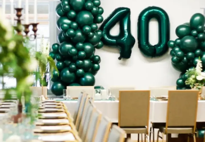 Uroczyste przyjęcie z okazji 40 urodzin w stylu lat 80. Zielone balony tworzą łuk z liczbą 40. Stoły nakryte do kolacji.