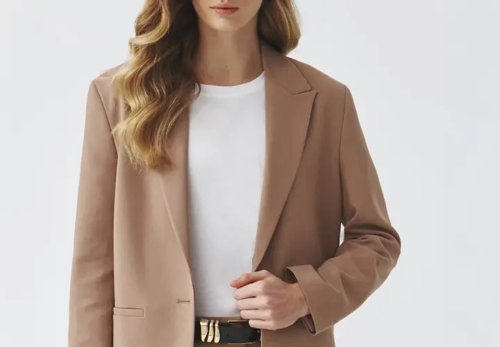 Elegancka brązowa marynarka w połączeniu z białą koszulką i czarnym paskiem tworzy stylową, minimalistyczną stylizację.