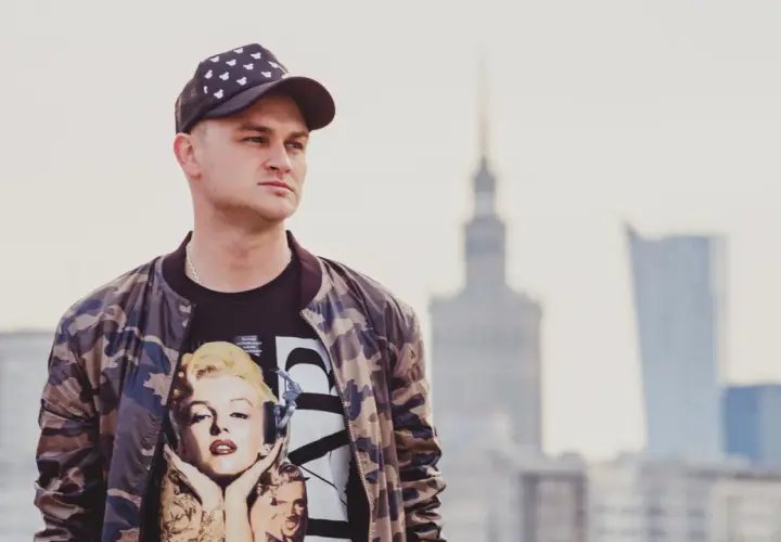 Młody mężczyzna w czapce z daszkiem i bluzie z Marilyn Monroe. Pokazuje, jak nosić czapkę z daszkiem w miejskim stylu.