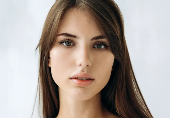 Delikatna, soft girl o zielonych oczach i brązowych włosach, z subtelnym makijażem.