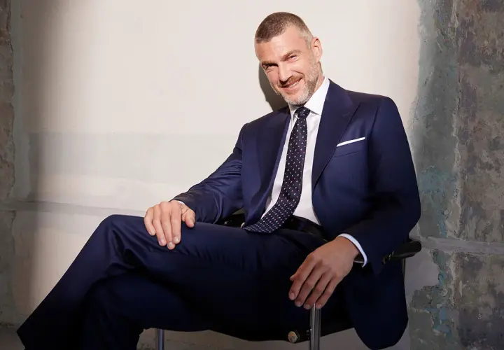 Elegancki mężczyzna w granatowym garniturze i wzorzystym krawacie. Idealny przykład, jak dobrać krawat do garnituru, by stworzyć spójną stylizację.