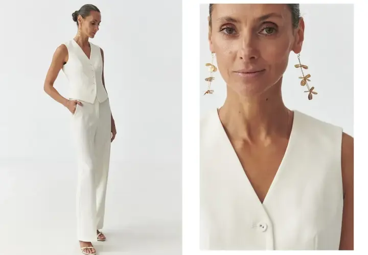 Elegancka stylizacja: jak nosić kamizelkę damską w białym total looku. Modelka prezentuje białą kamizelkę i spodnie, uzupełnione złotą biżuterią.