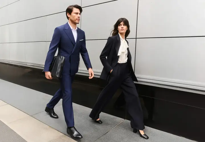 Para idąca w stylu business formal. Mężczyzna w granatowym garniturze, kobieta w ciemnym.