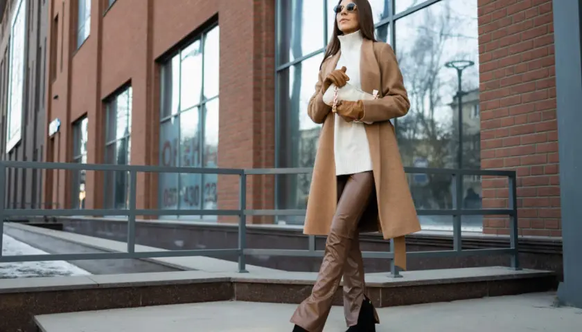 Elegancka kobieta w płaszczu i brązowych spodniach. Idealny przykład, z czym łączyć kolor karmelowy, tworząc stylowy look.