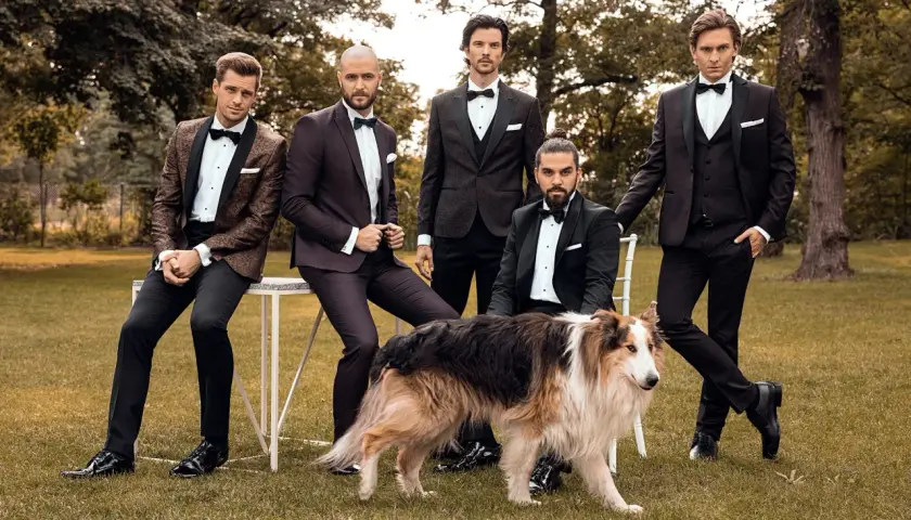 Eleganccy panowie w smokingach i błyszczących butach, a obok nich pies. Idealne połączenie stylu i klasy, pokazujące jakie buty do smokingu pasują najlepiej.
