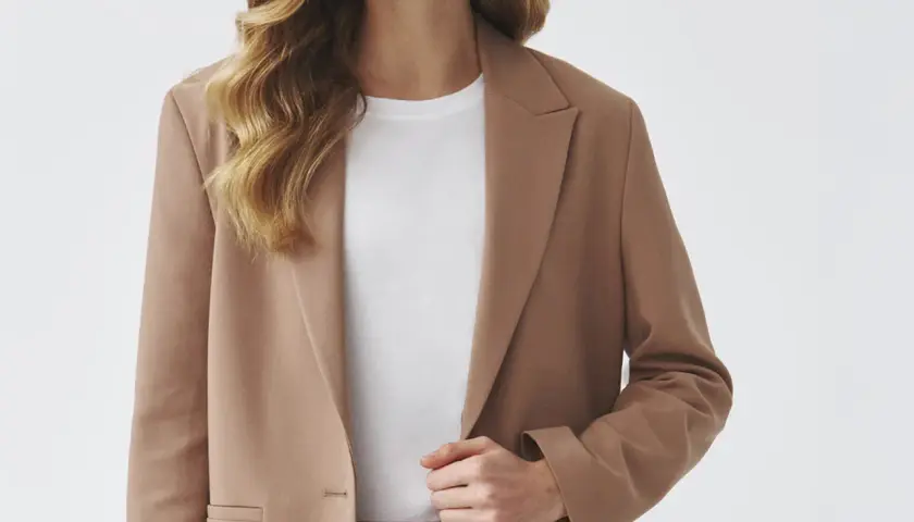 Elegancka brązowa marynarka w połączeniu z białą koszulką i czarnym paskiem tworzy stylową, minimalistyczną stylizację.