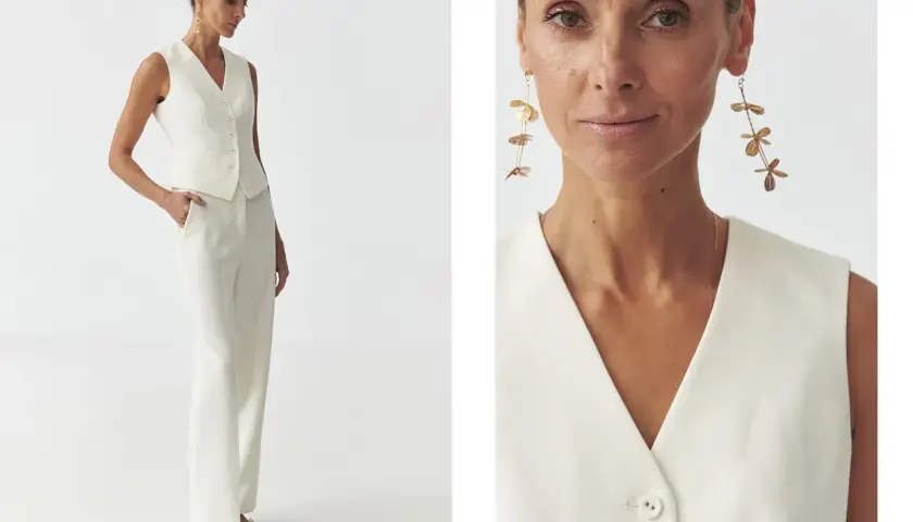 Elegancka stylizacja semi casual: biały garnitur z kamizelką i szerokimi spodniami, uzupełniony o długie, złote kolczyki.