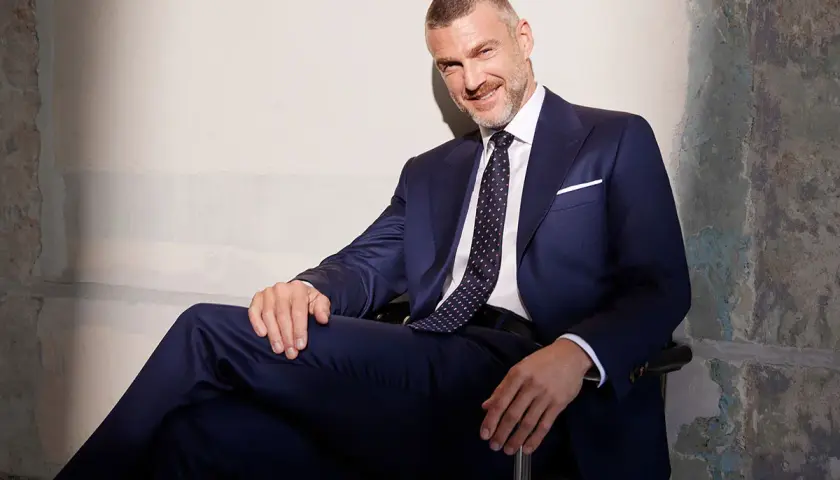 Elegancki mężczyzna w granatowym garniturze i wzorzystym krawacie. Idealny przykład, jak dobrać krawat do garnituru, by stworzyć spójną stylizację.