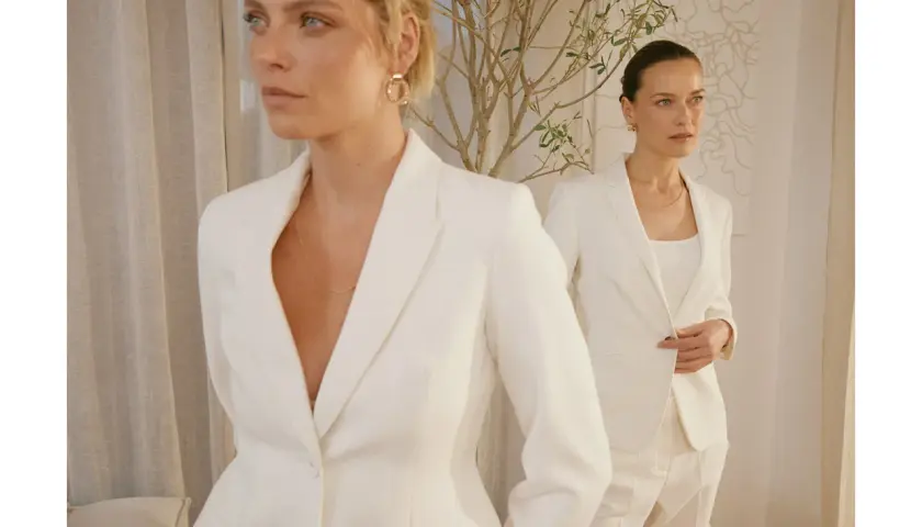 Dwie kobiety w białych garniturach, uosobienie power dressing. Eleganckie, pewne siebie, gotowe na podbój świata.