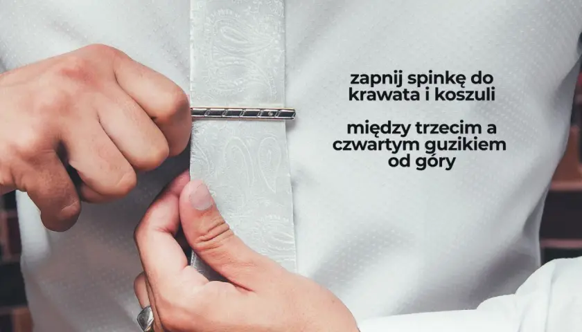 Mężczyzna zapina spinkę do krawata i koszuli między trzecim a czwartym guzikiem od góry. Elegancki sposób na noszenie spinki do krawata.