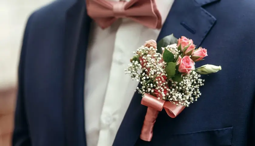 Elegancki granatowy garnitur z różową muszką i butonierką z drobnych różyczek. Jaka mucha do granatowego garnituru? Ta idealnie pasuje!