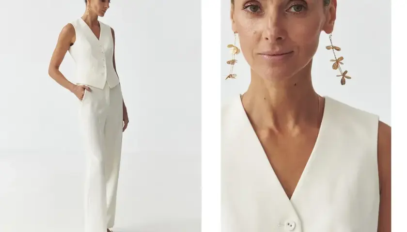 Elegancka stylizacja: jak nosić kamizelkę damską w białym total looku. Modelka prezentuje białą kamizelkę i spodnie, uzupełnione złotą biżuterią.