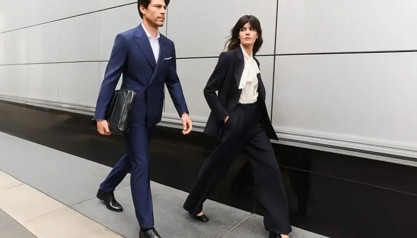 Para idąca w stylu business formal. Mężczyzna w granatowym garniturze, kobieta w ciemnym.