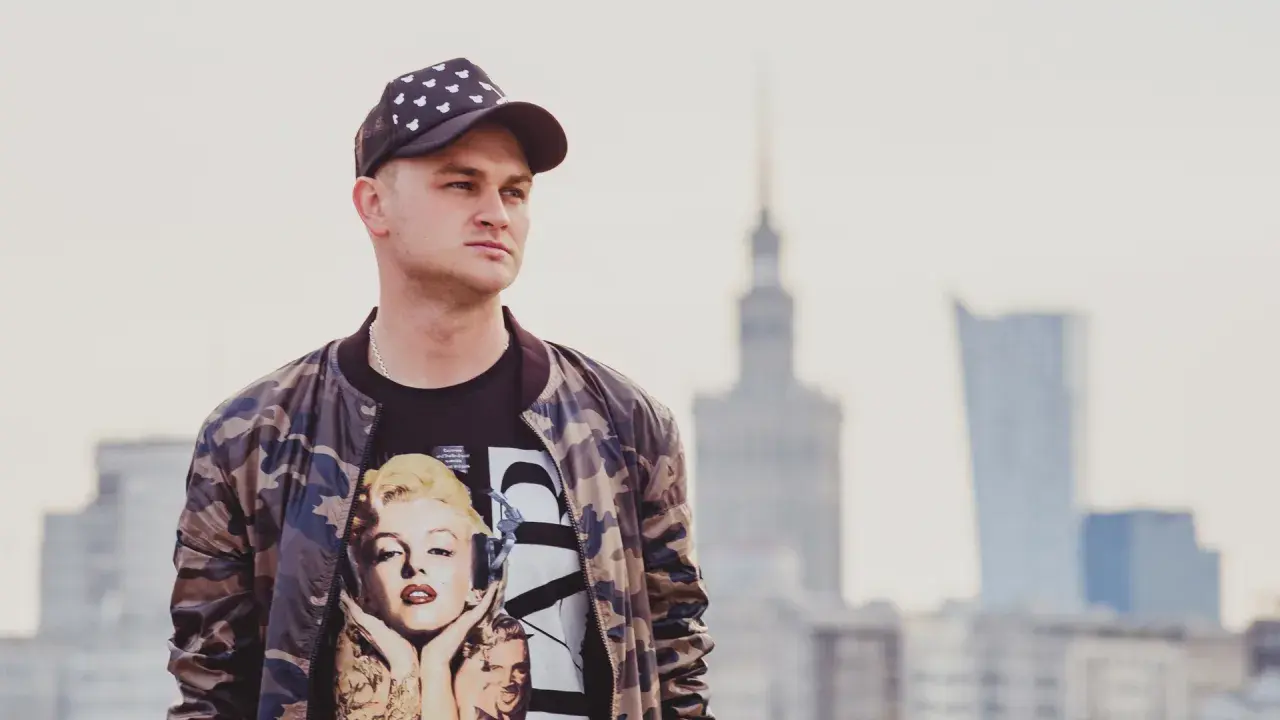 Młody mężczyzna w czapce z daszkiem i bluzie z Marilyn Monroe. Pokazuje, jak nosić czapkę z daszkiem w miejskim stylu.