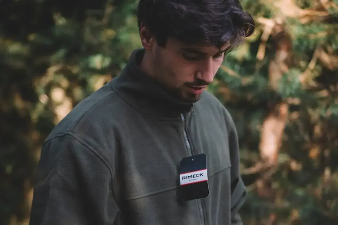 Mężczyzna w zielonej bluzie z metką. Idealna bluza do szarych dresów na jesienny spacer.