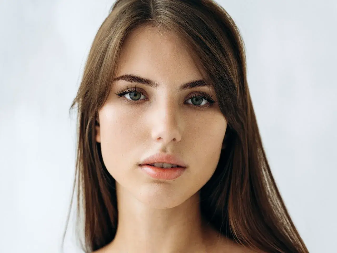Delikatna, soft girl o zielonych oczach i brązowych włosach, z subtelnym makijażem.