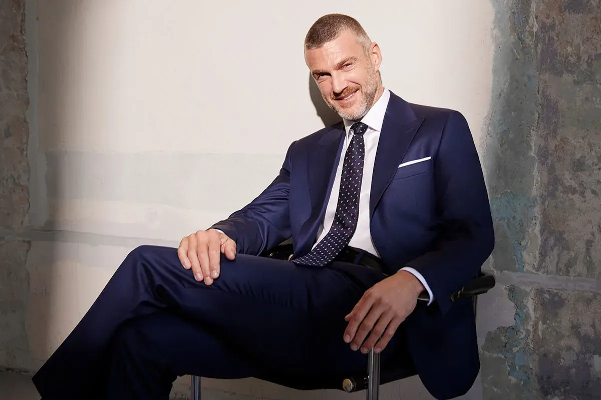 Elegancki mężczyzna w granatowym garniturze i wzorzystym krawacie. Idealny przykład, jak dobrać krawat do garnituru, by stworzyć spójną stylizację.