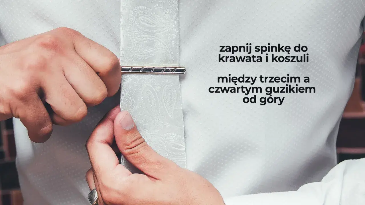 Mężczyzna zapina spinkę do krawata i koszuli między trzecim a czwartym guzikiem od góry. Elegancki sposób na noszenie spinki do krawata.