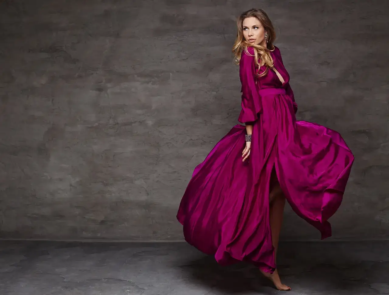 Kobieta w zwiewnej sukni w kolorze amarantowym wiruje, ukazując elegancję i dynamikę.